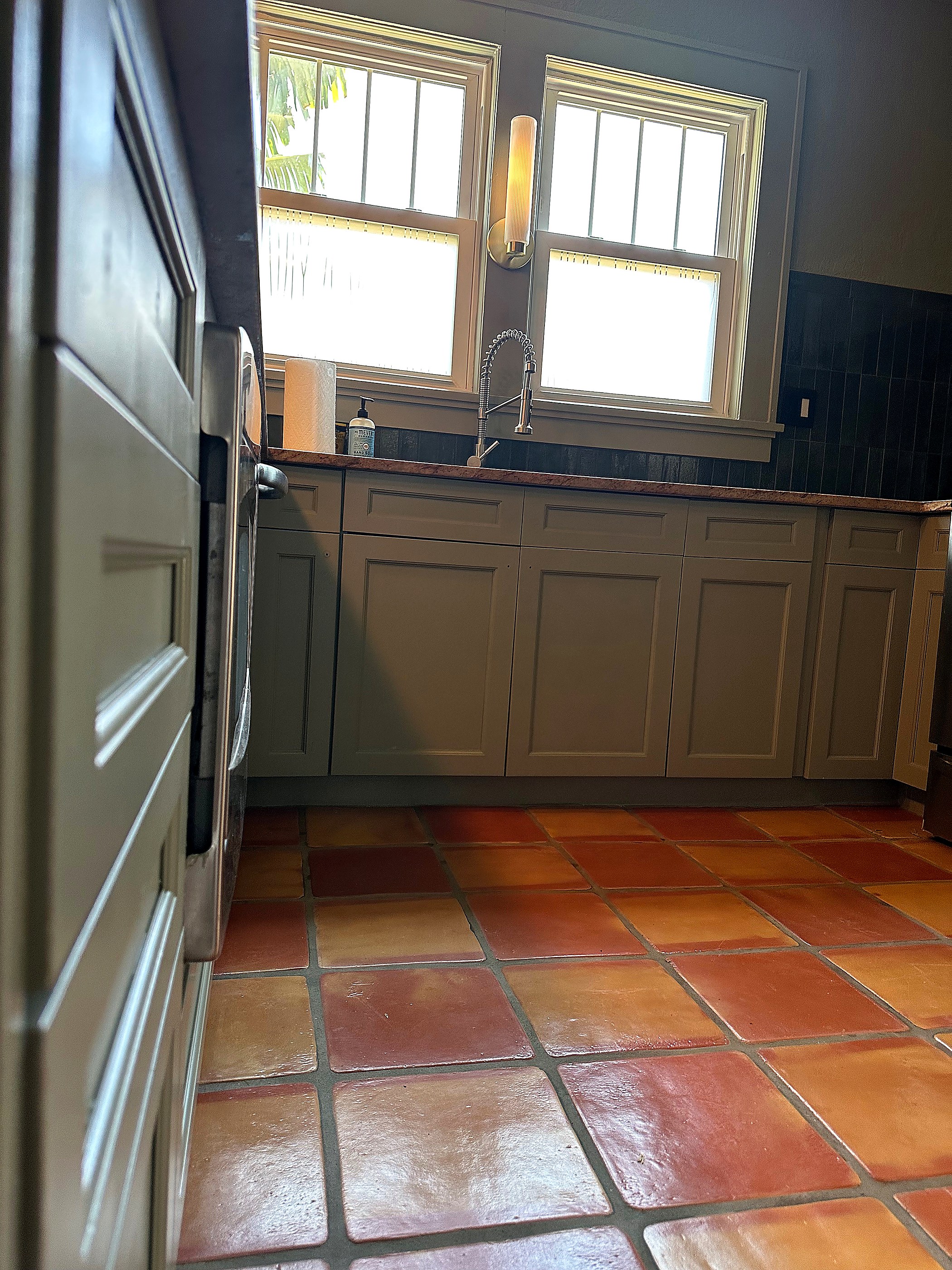 Sage kitchen with refinished surfaces and clean sink wall